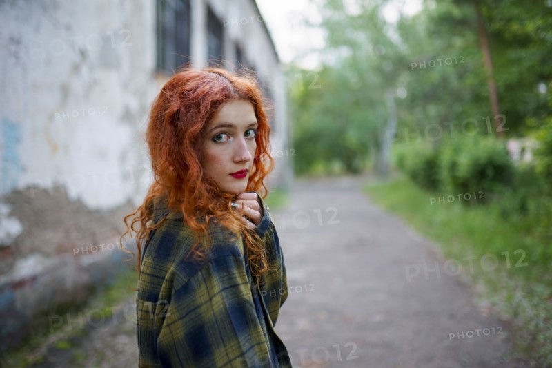 Redhaired woman posing next to old house