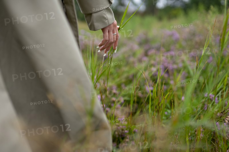 Close-up of woman in trench coat touching grass