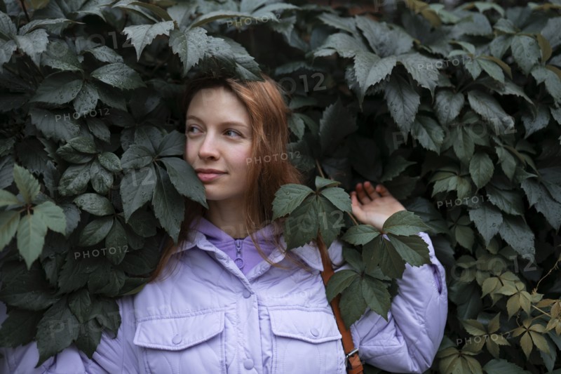 Portrait of woman in purple jacket against tree