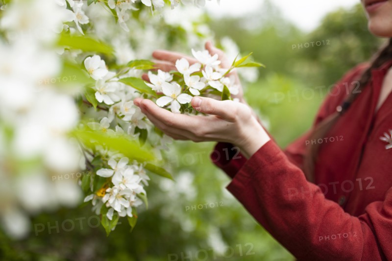 Young woman touching tree in blossom