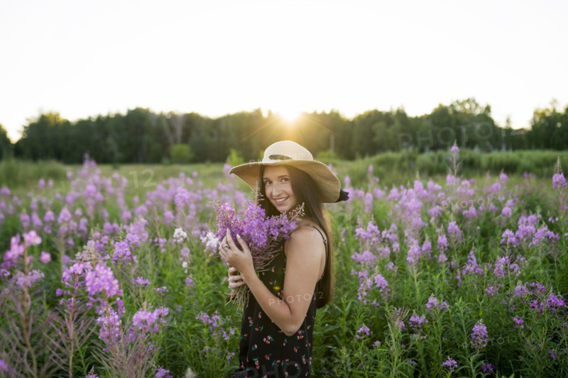 Portrait of smiling woman with flowers on meadow