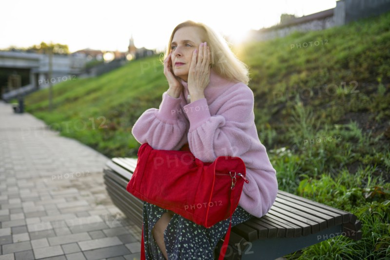 Serious woman sitting on bench at sunrise