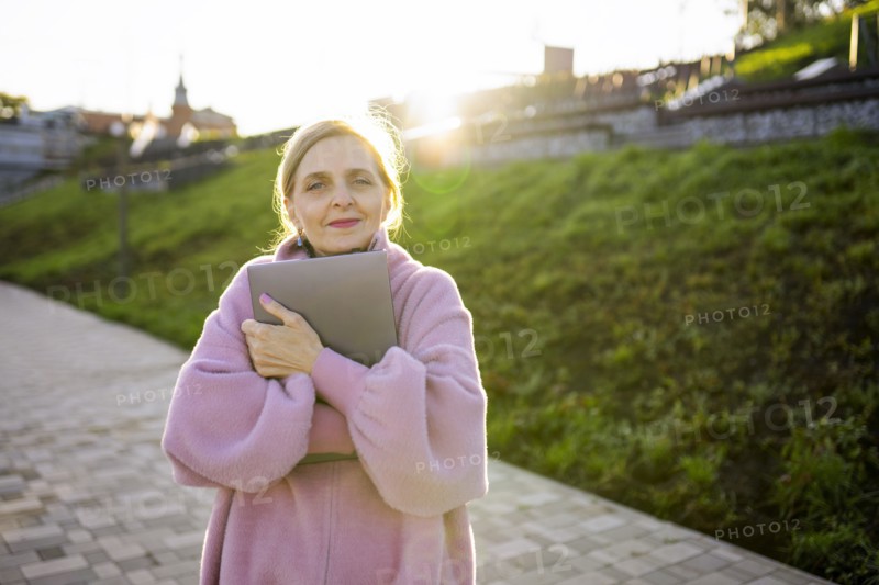 Woman embracing laptop while standing outdoors at sunrise