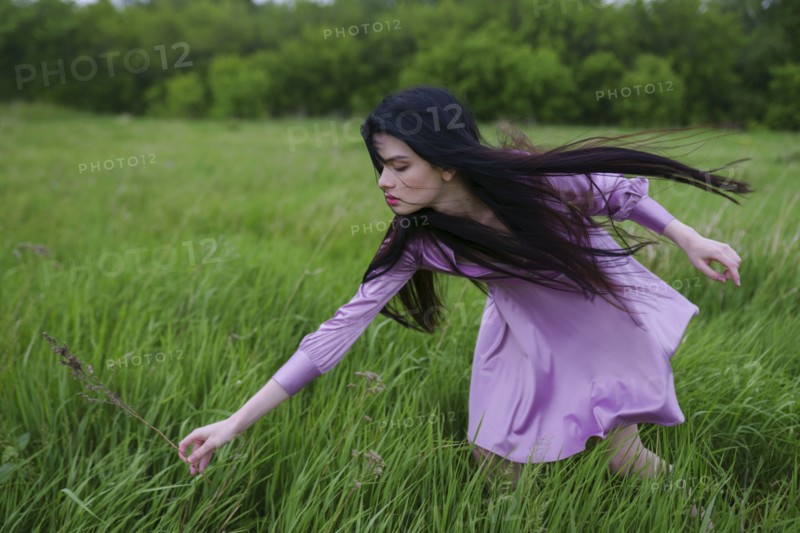Portrait of young woman picking grass on meadow