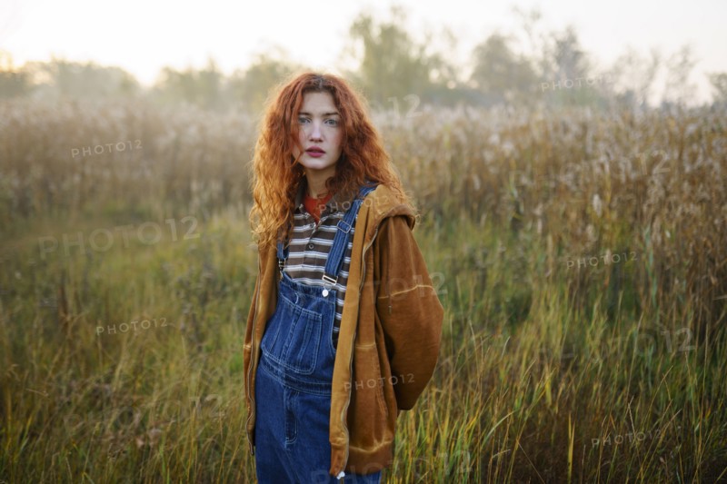Portrait of young woman standing in field at dawn