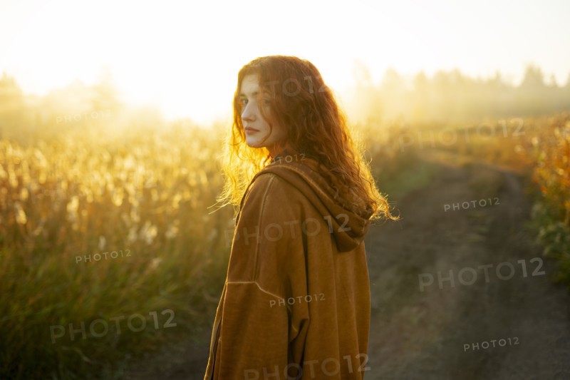 Portrait of serious woman standing in field at sunrise