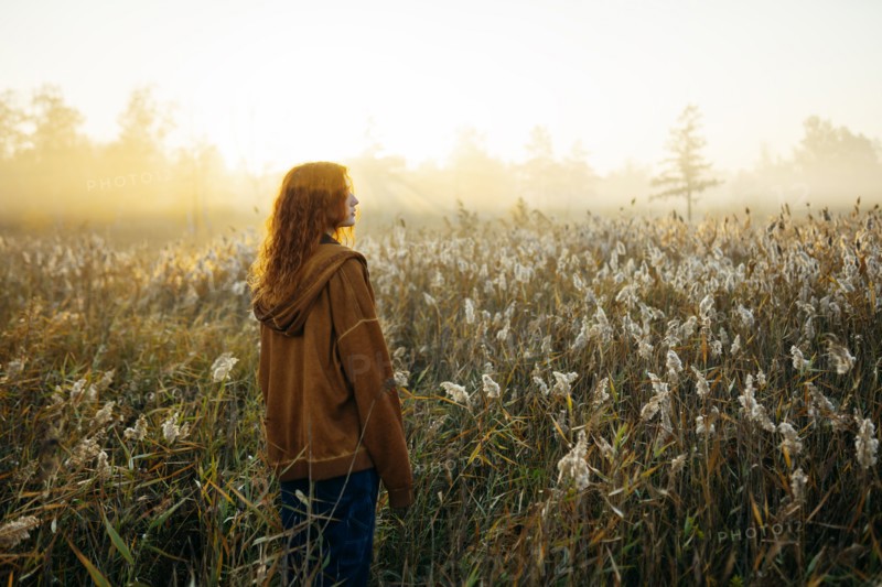 Rear view of woman standing in field at sunrise