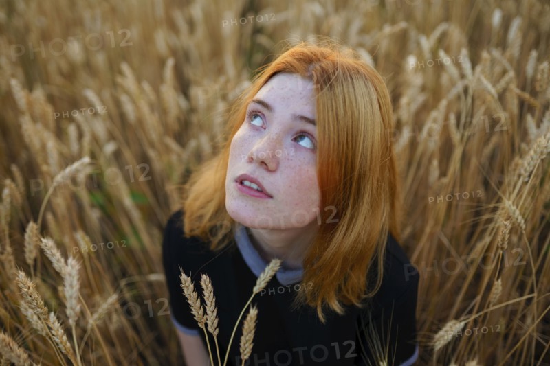 Thoughtful woman looking up while standing in agricultural field