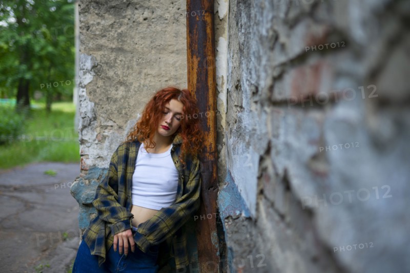 Tired woman with closed eyes leaning on building wall