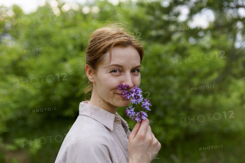 Portrait of smiling woman smelling lilac flower
