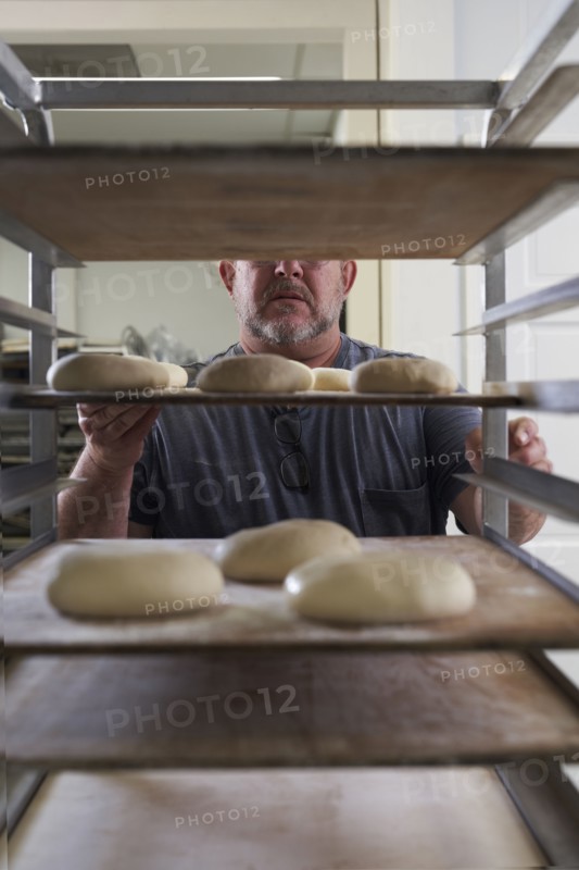 Baker standing with bread dough on tray
