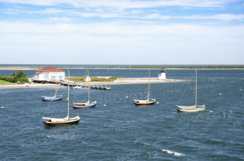 Sailboats anchored in sea near lighthouse and pier, Nantucket, Massachusetts, USA