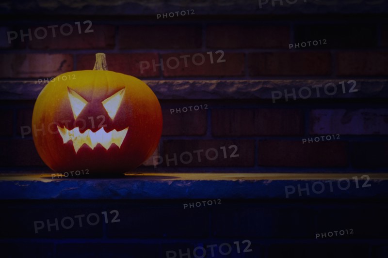 Illuminated Halloween jack-o-lantern on porch at night, Chatham, New Jersey, USA