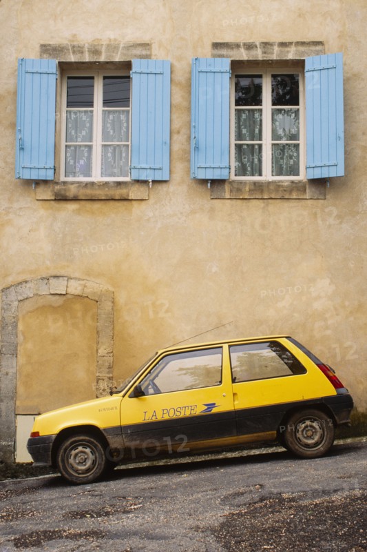 Yellow postal delivery vehicle parked outside a townhouse,  Bonnieux, , France