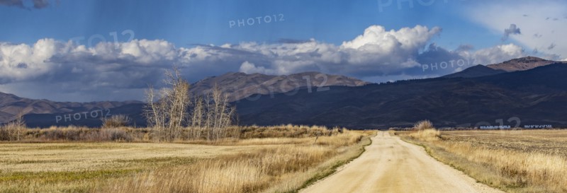 Empty dirt road leading to foothills under stormy skies, Fairfield, Idaho, USA
