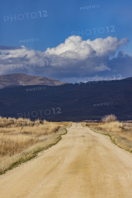 Empty dirt road leading to foothills under stormy skies, Fairfield, Idaho, USA