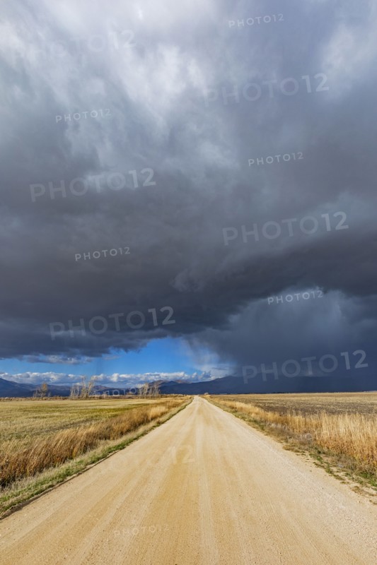 Storm clouds over empty dirt road in rural landscape, Fairfield, Idaho, USA