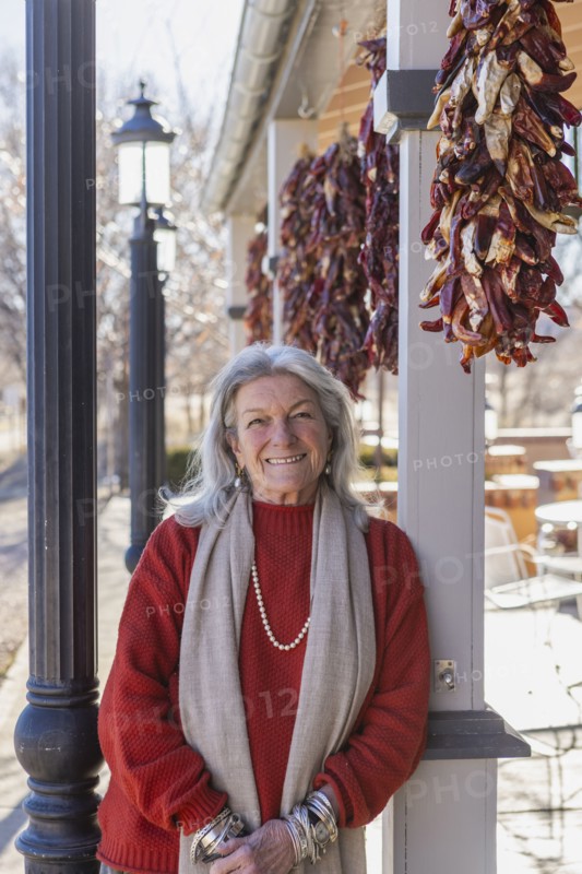 Portrait of smiling woman leaning against column at sidewalk cafe, Lamy, New Mexico, USA