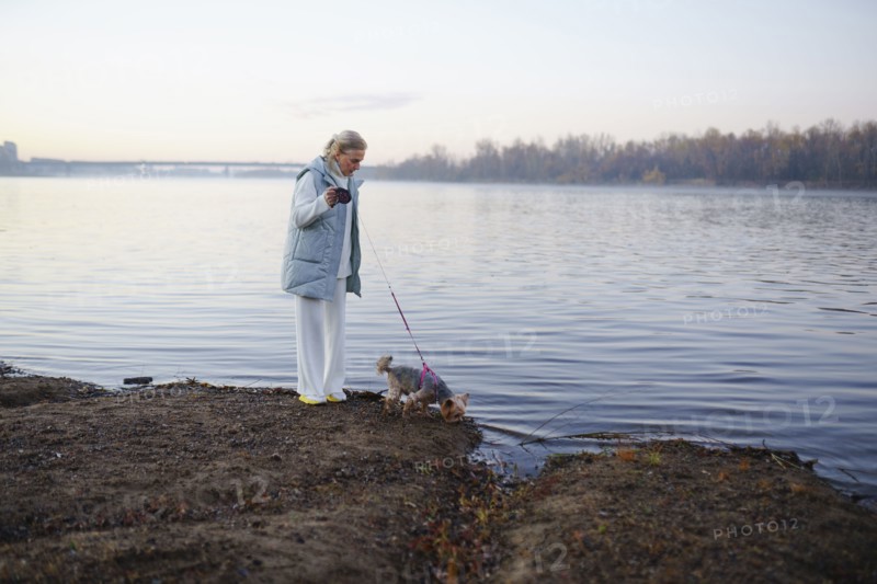 Woman with Yorkshire Terrier on lakeshore, Omsk, , Russia
