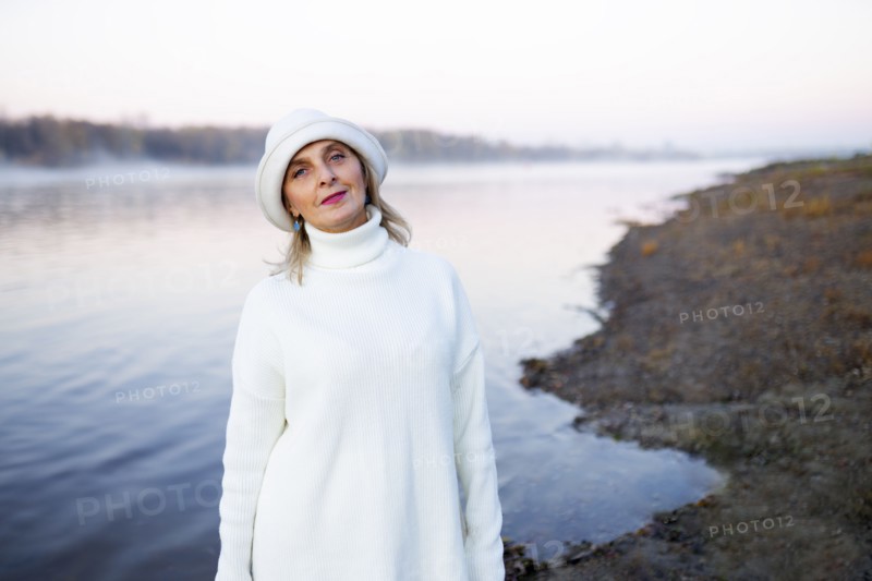 Portrait of woman in white hat and sweater on lakeshore, Omsk, , Russia