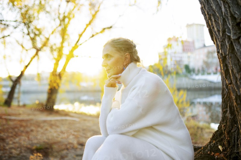 Woman in white sweater sitting by river in autumn, Omsk, , Russia