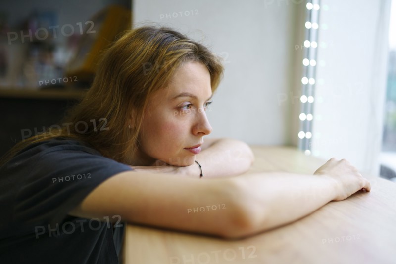 Woman leaning on window sill and looking through window, Omsk, , Russia
