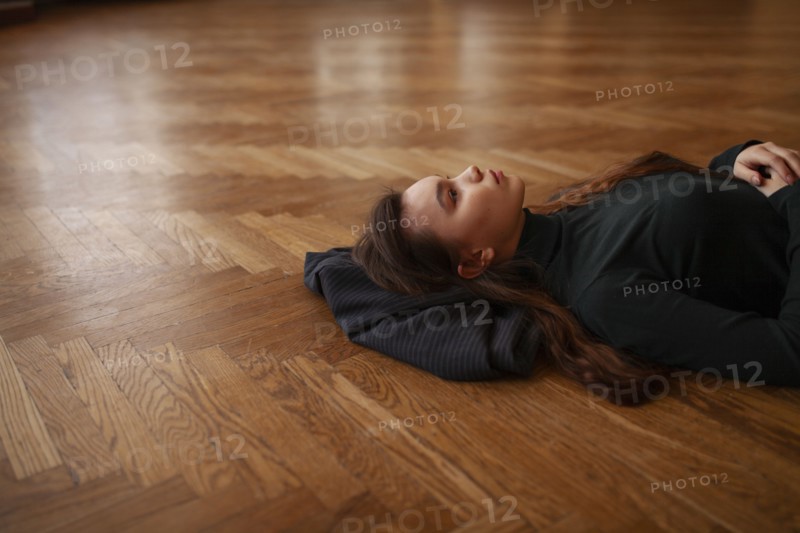 Pensive woman lying on parquet floor, Novosibirsk, , Russia