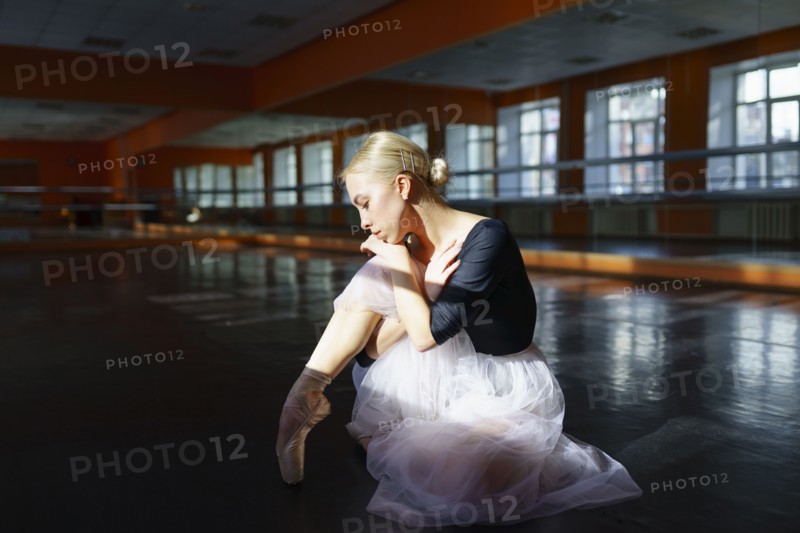 Pensive ballerina sitting on floor in ballet studio, Omsk, , Russia