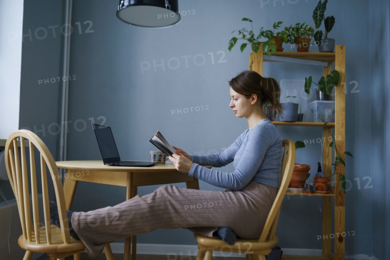 Woman reading at table at home, Omsk, , Russia