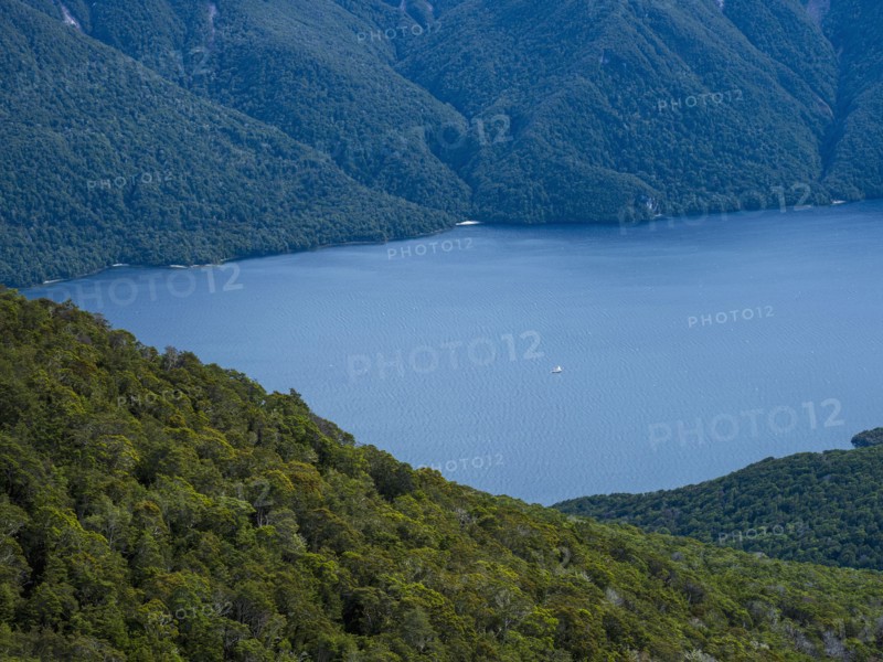 Blue lake surrounded with green hills, Te Anau, Fiordland, New Zealand