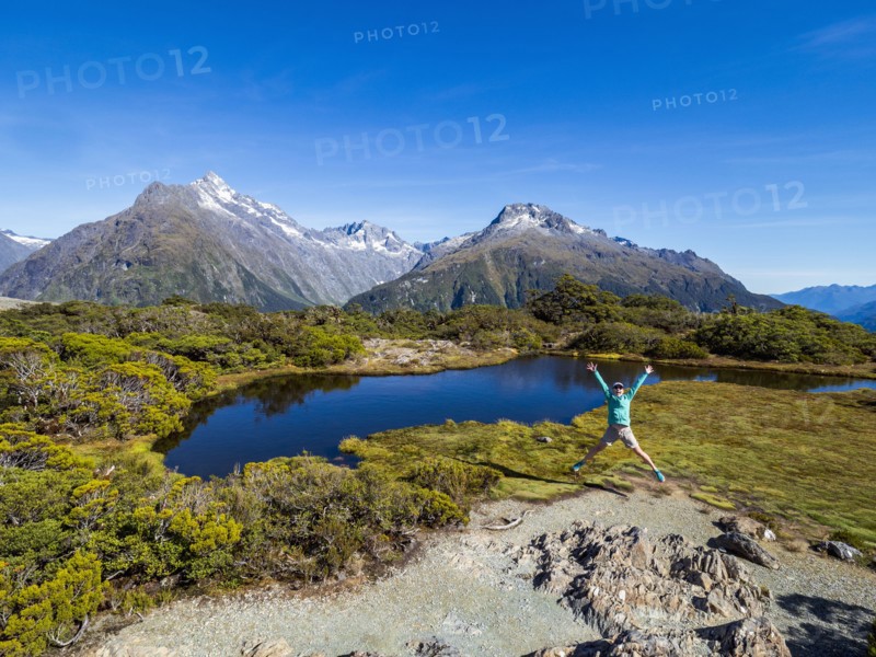 Woman jumping in landscape in Fiordland National Park, Te Anau, Fiordland, New Zealand