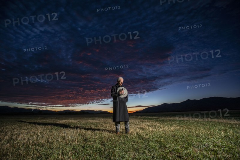 USA, Idaho, Bellevue, Rancher in overcoat standing in field, holding hat over heart, Bellevue, Idaho, USA