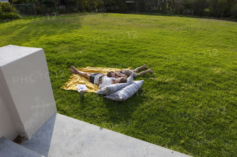 Mother and son lying on blanket in back yard, Hermanus, , South Africa