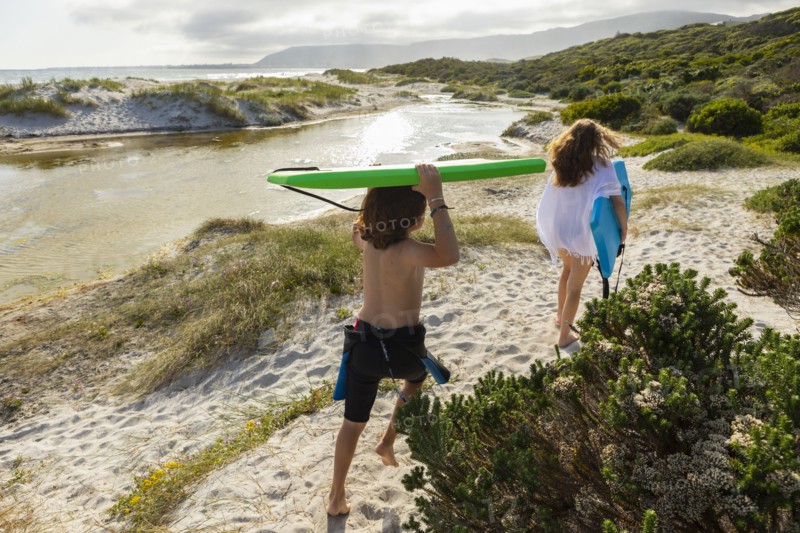 South Africa, Hermanus, Brother and sister walking on beach with body boards, Hermanus, , South Africa