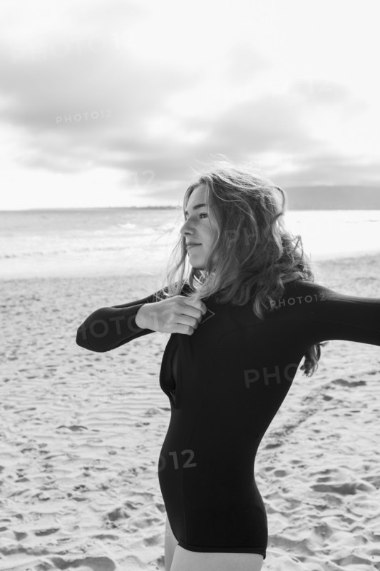 South Africa, Hermanus, Teenage girl putting on wetsuit on beach, Hermanus, , South Africa