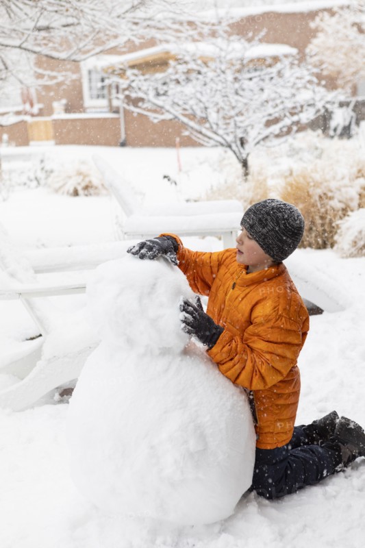 Boy building snowman, Santa Fe, New Mexico, USA