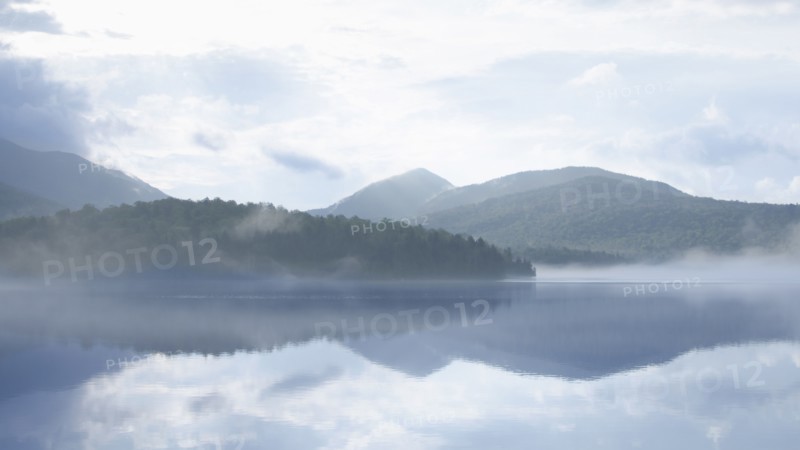 USA, New York, Lake Placid, Calm Lake Placid reflecting hills and clouds, Lake Placid, New York, USA