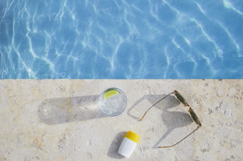 Overhead view of sunglasses, sun cream and drink by pool, , St. John, US Virgin Islands