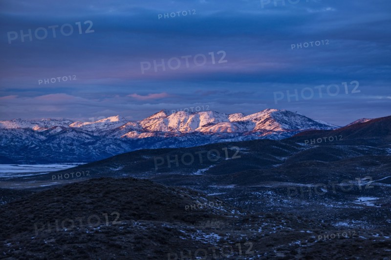 Sunset light on distant snowy mountains outside Mountain Home, Mountain Home, Idaho, USA