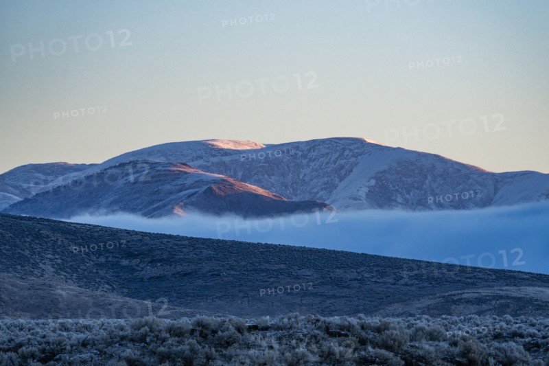 Low hanging cloud in fold between foothills covered with frost at sunrise, Picabo, Idaho, USA