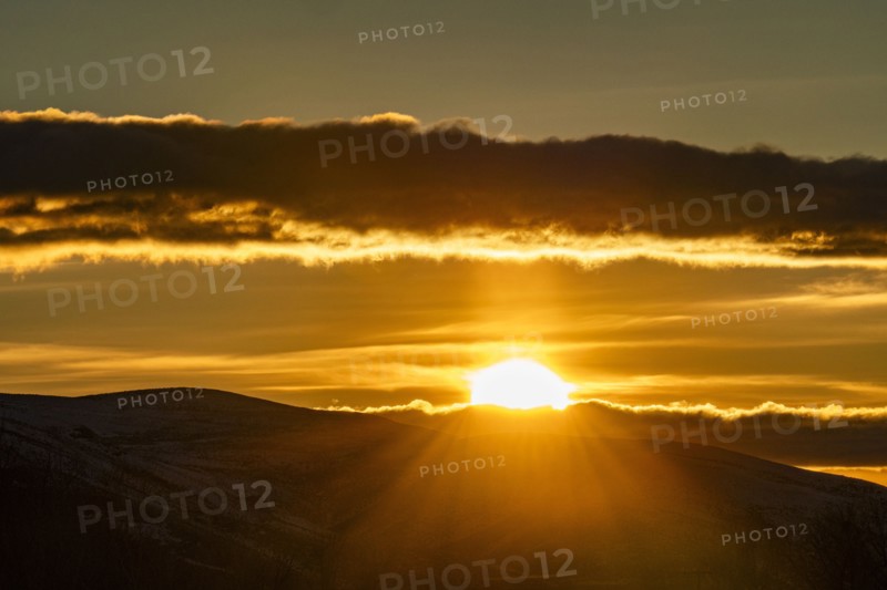 Clouds above golden sun setting behind hills, Bellevue, Idaho, USA