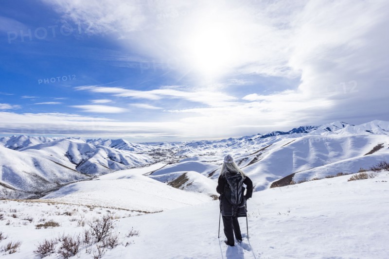 Rear view of woman with snowshoes standing on top of Carbonate Mountain, looking at Croy Canyon, Hailey, Idaho, USA