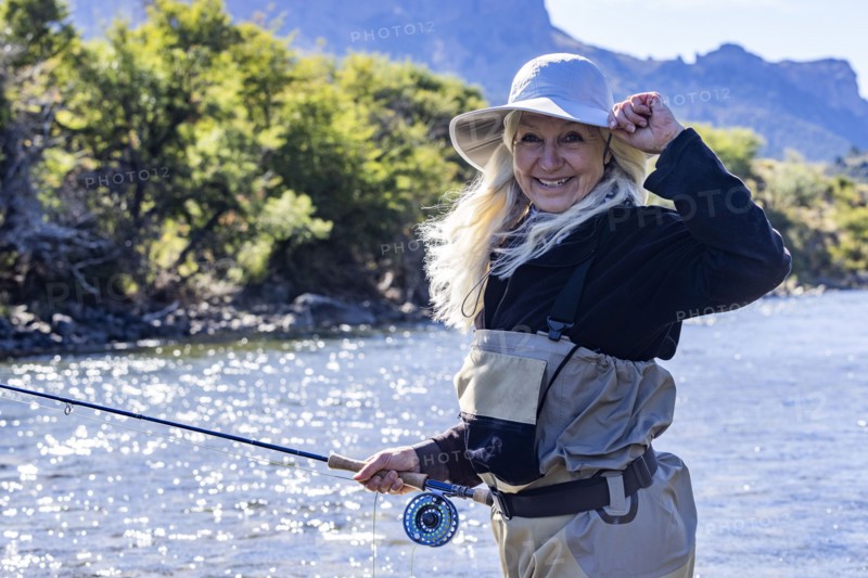 Portrait of smiling woman in white hat fly fishing on Traful River, Estancia Arroyo Verde, Nequen Province, Argentina