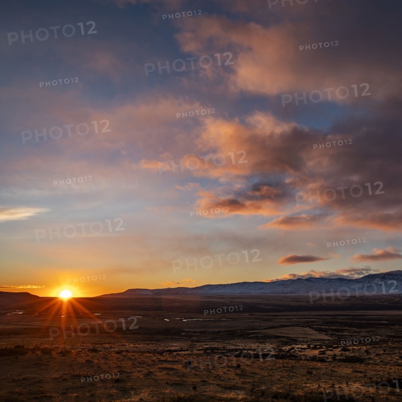 Argentina, Santa Cruz, El Calafate, Sun rising above plain landscape with mountains in distance, El Calafate, Santa Cruz, Argentina