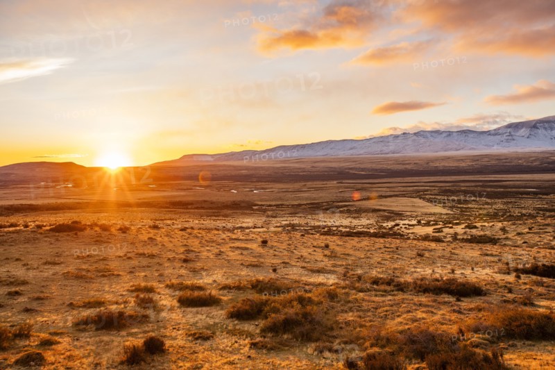 Argentina, Santa Cruz, El Calafate, Sun rising above plain landscape with mountains in distance, El Calafate, Santa Cruz, Argentina