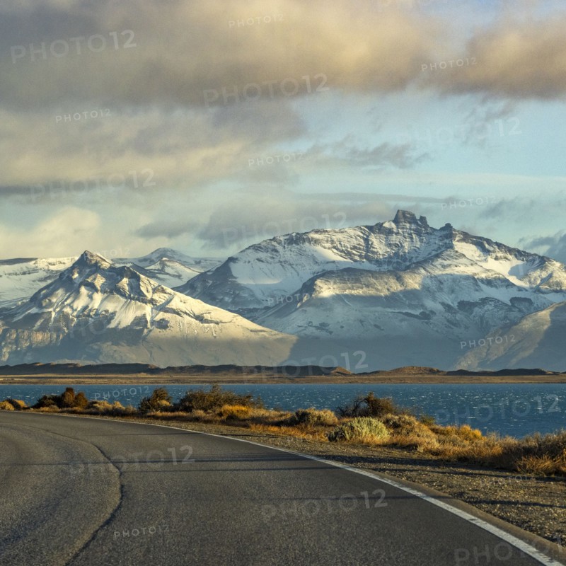 Argentina, Santa Cruz, El Calafate, Empty road with lake and snowcapped mountains in background, El Calafate, Santa Cruz, Argentina
