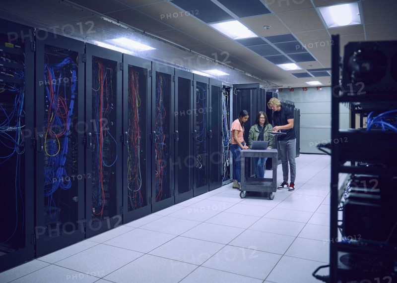 Group of technicians using laptop in server room 
St, George, Utah, USA