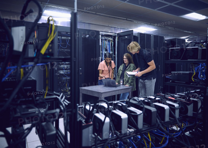Group of technicians using laptop in server room 
St, George, Utah, USA