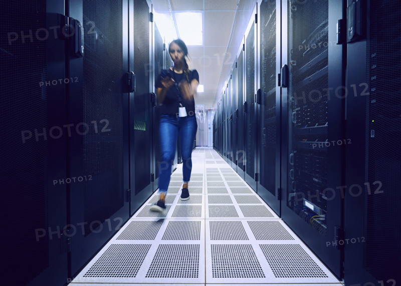 Female technician walking in server room 
St, George, Utah, USA