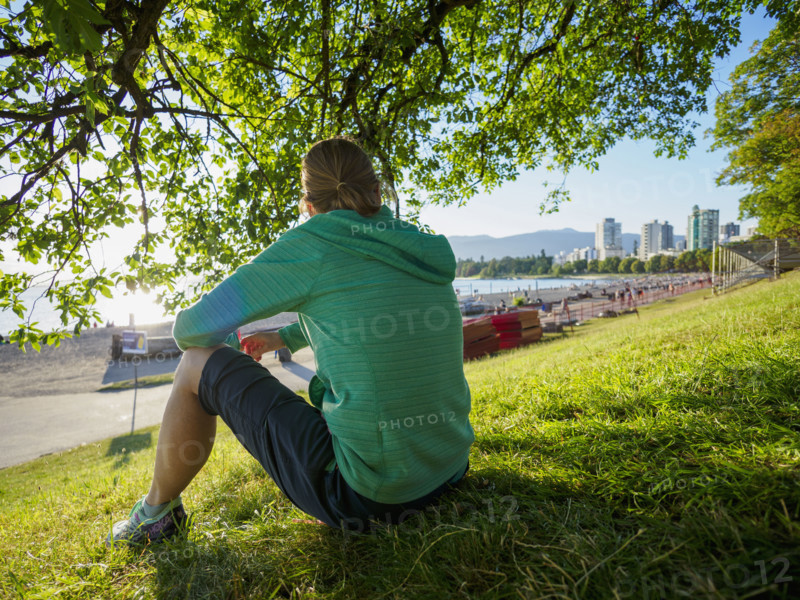 Rear view of woman sitting on lawn near coast
Vancouver, British Columbia, Canada